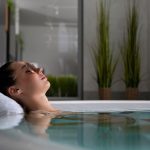 A woman relaxes in a jacuzzi with sunglasses, embodying self-care and relaxation.
